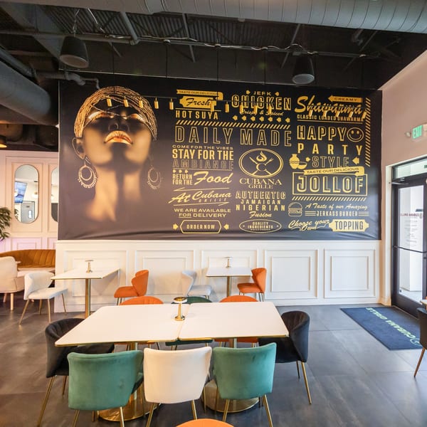 Cubana Grille dining area with modern tables, colorful chairs, and a large wall mural featuring menu items.