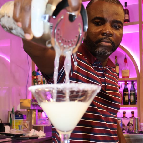 Bartender pouring a Caribbean cocktail from a shaker into a martini glass at Cubana Grille.