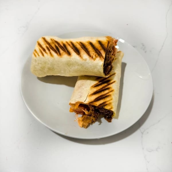 Two grilled Caribbean wraps with visible filling, served on a white plate.