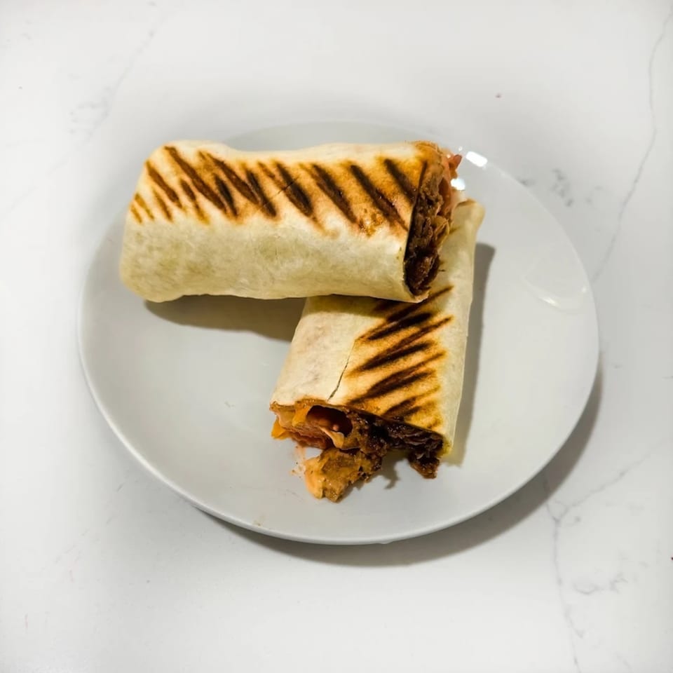 Two grilled Caribbean wraps with visible filling, served on a white plate.