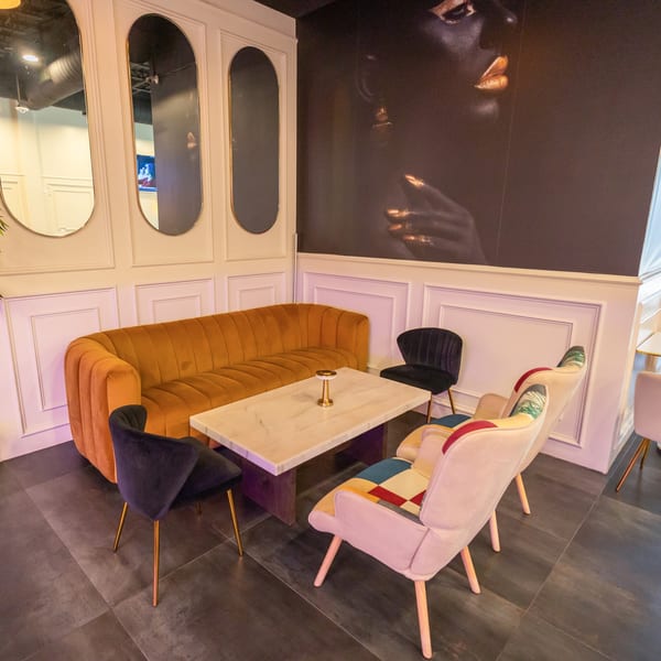 Cubana Grille's lounge area with a mustard yellow sofa, marble table, and colorful chairs.