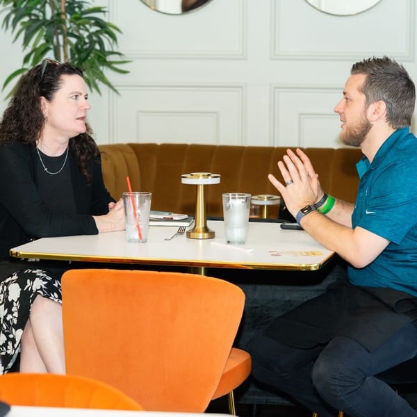 Two people conversing at a table in Cubana Grille, with drinks and a modern table lamp.