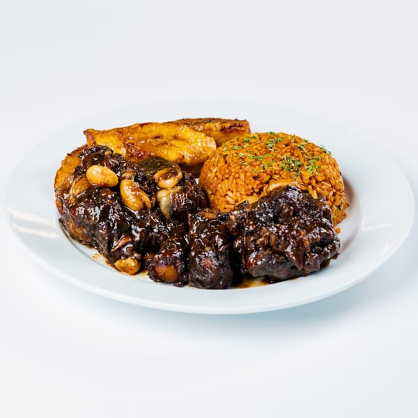 Cubana Grille's Caribbean oxtail stew with rice and plantains on a white plate.